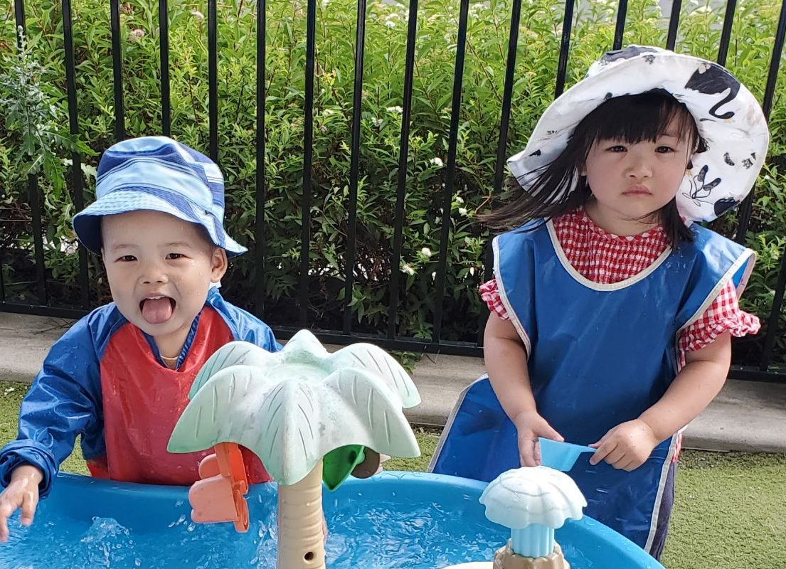Two children playing at a water table
